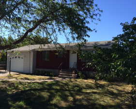 Single story home featuring an attached garage, a front lawn, and driveway