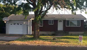 Ranch-style home with a front yard, asphalt driveway, an attached garage, and entry steps