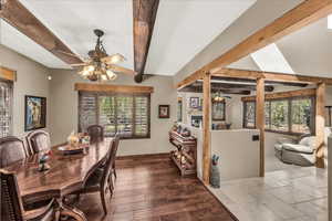 Dining space with a ceiling fan, beamed ceiling, and stone tile floors