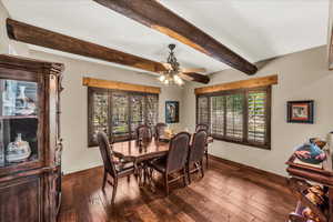 Dining area featuring dark wood finished floors, beam ceiling, and ceiling fan