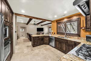 Kitchen featuring dark wood finish cabinetry, ventilation hood, a peninsula, recessed lighting, and stainless steel appliances