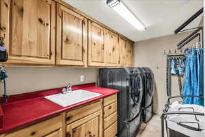 Laundry room featuring washer and dryer, a textured ceiling, cabinet space, and electric panel