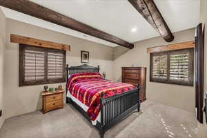 Bedroom with light carpet and beamed ceiling