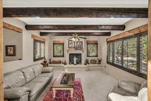 Carpeted living room with a glass covered fireplace and baseboards