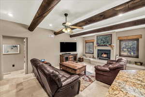 Living area featuring a glass covered fireplace, beamed ceiling, ceiling fan, and recessed lighting