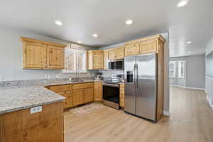 Kitchen with light stone countertops, stainless steel appliances, light wood-type flooring, light wood finish cabinets, and recessed lighting