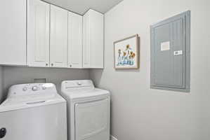 Laundry area featuring electric panel, cabinet space, and washer and dryer
