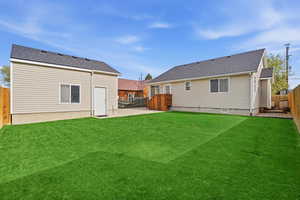 Back of property featuring a fenced backyard, a shingled roof, and a patio area