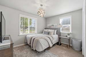 Bedroom featuring light colored carpet and hanging lights