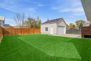 Fenced backyard featuring an outbuilding and a garage