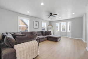 Living area with light wood finished floors, plenty of natural light, recessed lighting, and a ceiling fan