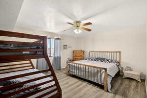 Bedroom featuring a textured ceiling, light wood-style floors, and ceiling fan