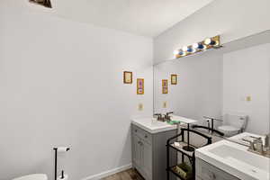 Bathroom featuring two vanities, light wood-type flooring, and a textured ceiling