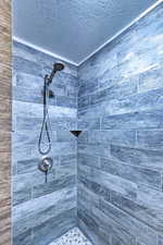 Bathroom featuring a textured ceiling and a tile shower