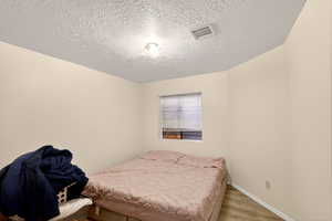 Bedroom featuring wood finished floors and a textured ceiling