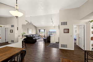 Living area with dark wood-type flooring, a high textured ceiling, and suspended lighting