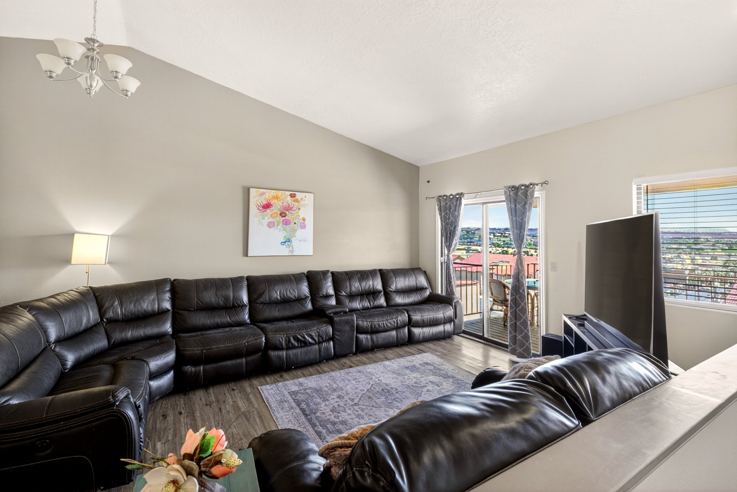 Living area with lofted ceiling, suspended lighting, and wood finished floors