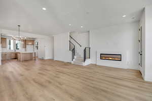 Unfurnished living room with a glass covered fireplace, light wood-style floors, and hanging lights