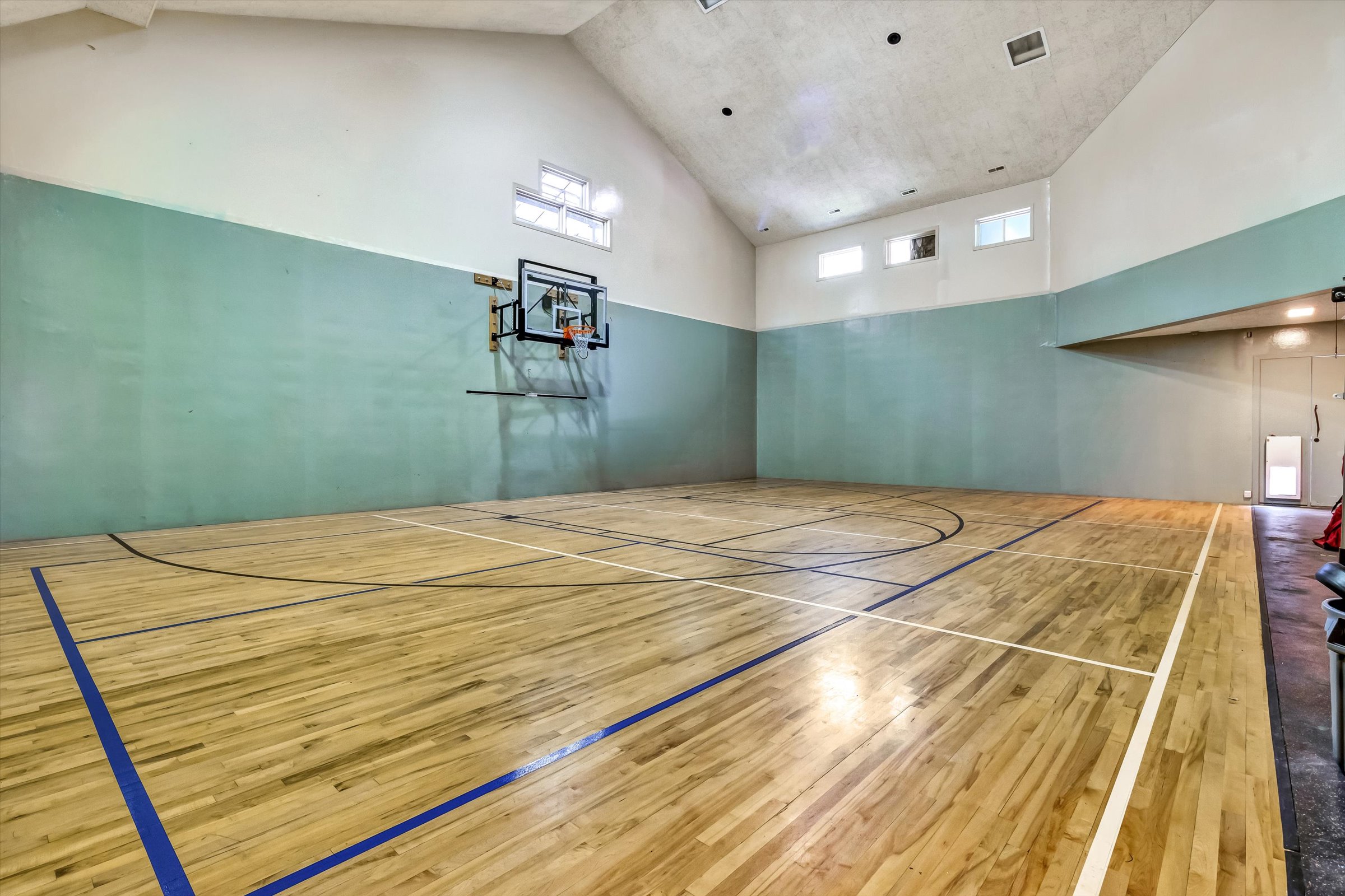 Heated and air-conditioned field house with professional floating maple court surface, striped for pickleball, basketball, and volleyball. Features outdoor access and rubberized area with power for exercise equipment.