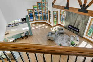 Living room with a tiled fireplace, a high ceiling, and light wood-style flooring