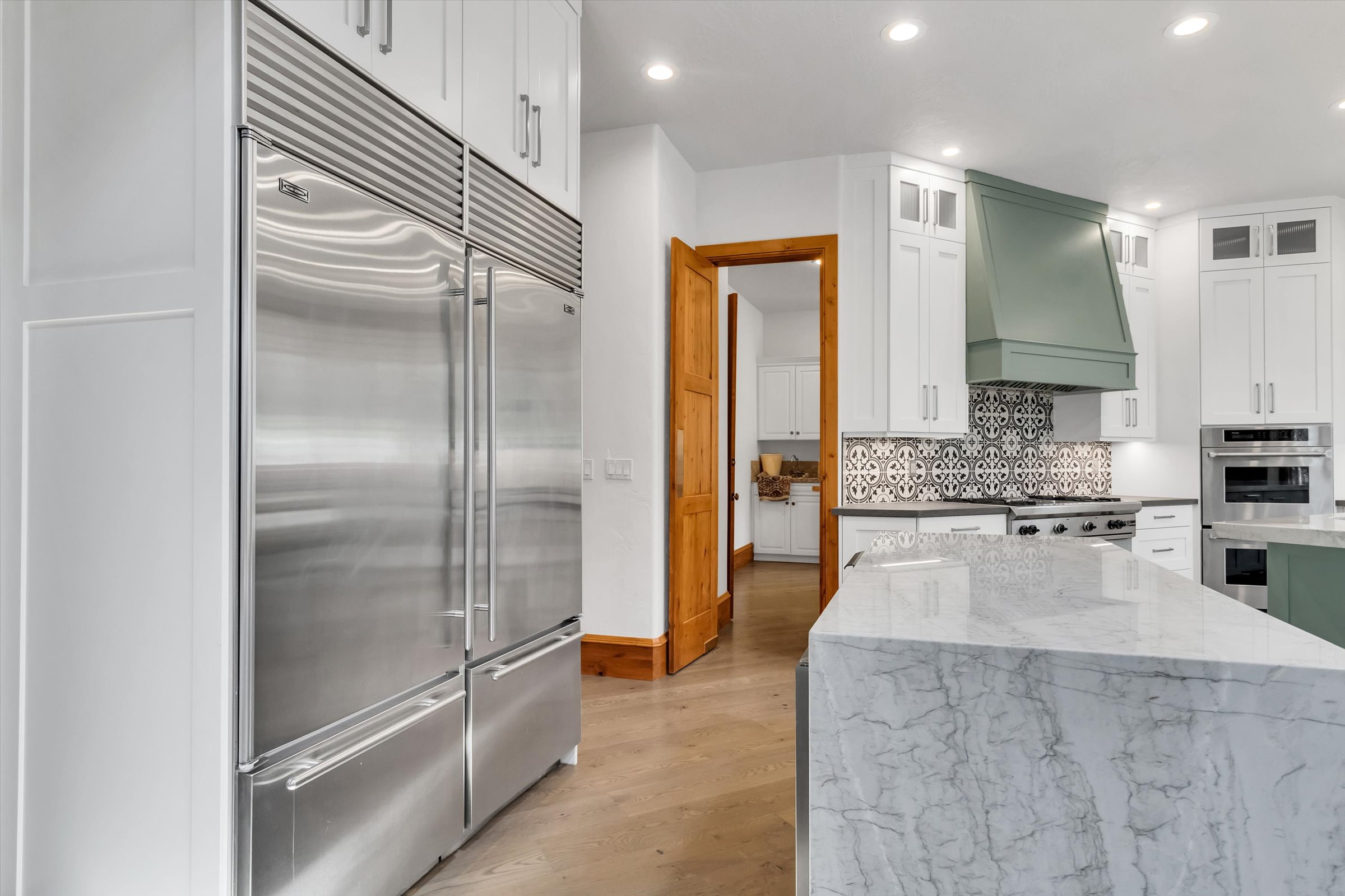 Massive twin Sub-Zero refrigerators, and a small secondary island with ice maker and beverage cooler.