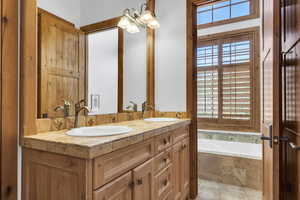 Bathroom featuring plenty of natural light, double vanity, a garden tub, and a chandelier
