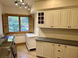 Kitchen featuring light wood-style flooring, white cabinetry, and glass fronted cabinets