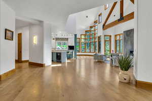 Living area featuring beverage cooler, light wood-type flooring, vaulted ceiling, and a fireplace