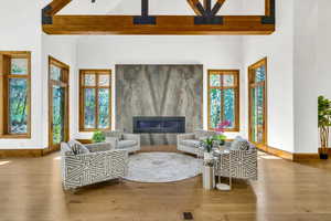 Living area featuring a large fireplace, wood finished floors, and a high ceiling
