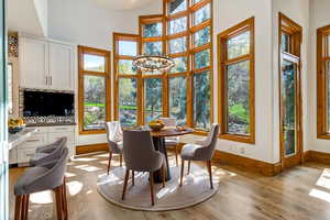 Dining area with suspended lighting, light wood finished floors, and a high ceiling. (virtual stanging)