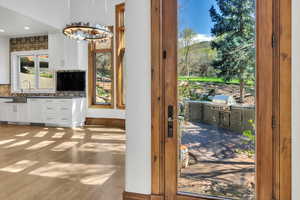 Doorway with wood finished floors and suspended lighting