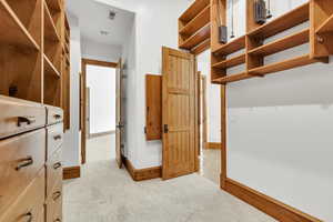 Walk in closet with light colored carpet