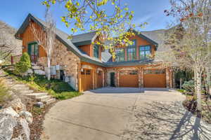 Craftsman house with stone siding, an attached garage, driveway, roof with shingles, and french doors