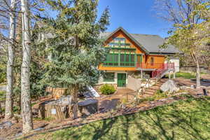 Back of property featuring stone siding, a lawn, and roof with shingles