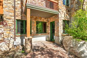 Entrance to property with stone siding and a patio