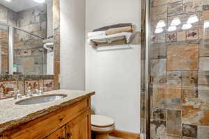 Full bathroom featuring a textured wall, vanity, and a stall shower