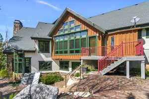 Rear view of property featuring roof with shingles, a chimney, a patio area, and board and batten siding