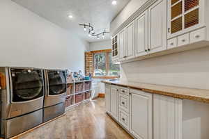Laundry area featuring light wood-style floors, independent washer and dryer, recessed lighting, cabinet space, and a textured ceiling