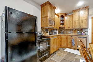 Kitchen featuring black appliances, light stone finish floors, decorative backsplash, and open shelves