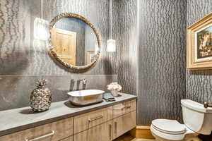Half bath featuring wallpapered walls and vanity