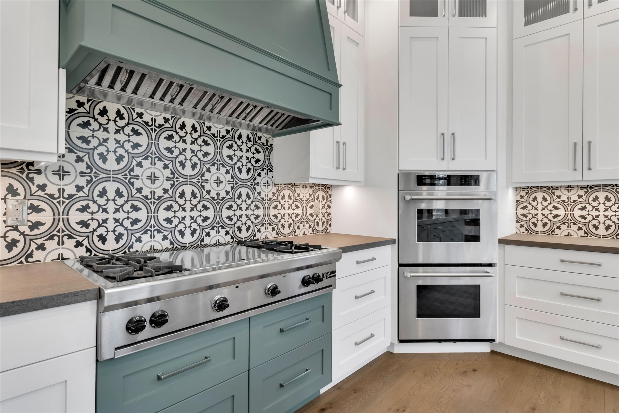 Professional Wolf cooktop with griddle, custom ventilation hood, and dual convection ovens.