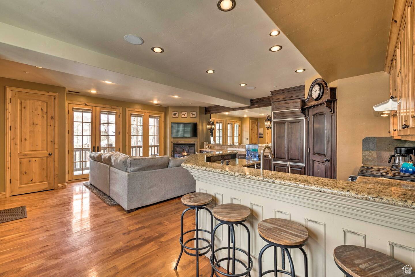 Kitchen with a kitchen breakfast bar, light stone countertops, recessed lighting, extractor fan, and a peninsula