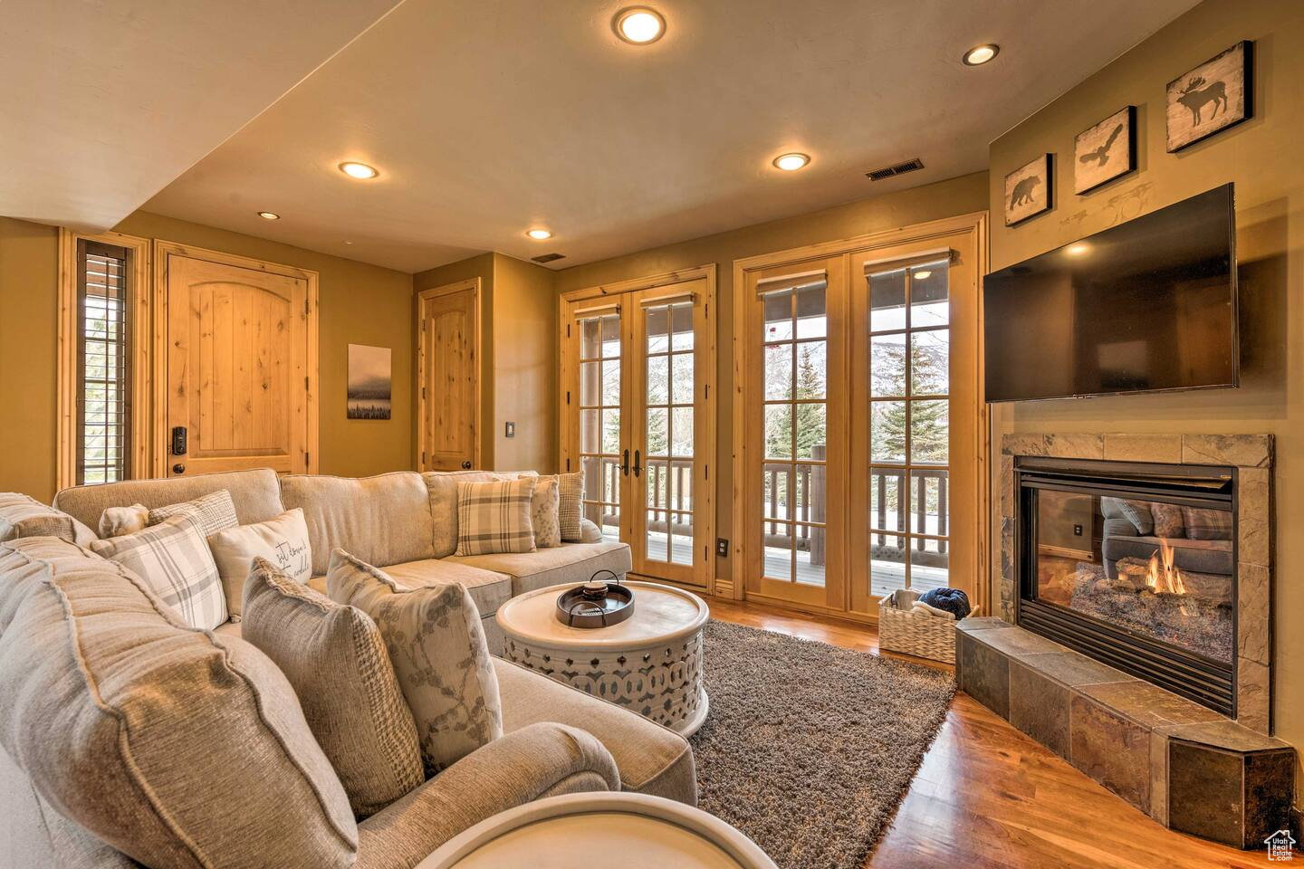 Living area featuring wood finished floors, recessed lighting, a tile fireplace, and french doors