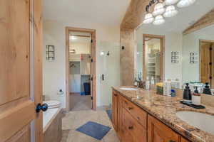Bathroom featuring a walk in closet, a shower stall, double vanity, and light tile patterned floors