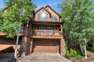 View of front of house featuring concrete driveway, an attached garage, a porch, and stone siding