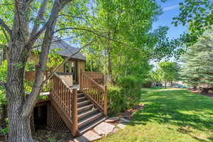 View of grassy yard featuring stairs and a deck
