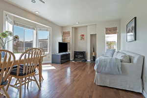 Living room with healthy amount of natural light, hardwood / wood-style flooring, a wood stove, and recessed lighting