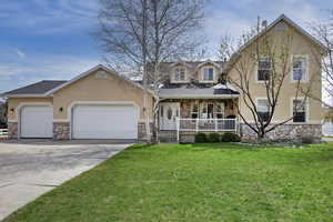 View of front of home with stone siding, a porch, a garage, concrete driveway, and stucco siding