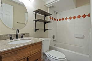 Full bathroom featuring a textured wall, vanity, and shower / bathtub combination with curtain