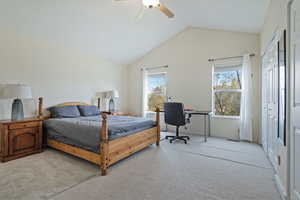 Bedroom with light colored carpet, a ceiling fan, a closet, and a desk